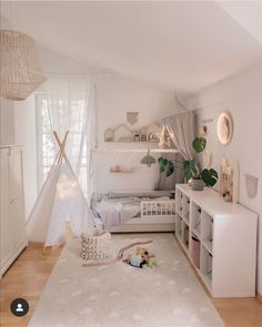 a bedroom with white walls and wooden flooring has a teepee tent in the corner