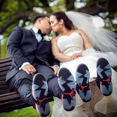 a bride and groom sitting on a park bench with their feet up in the air