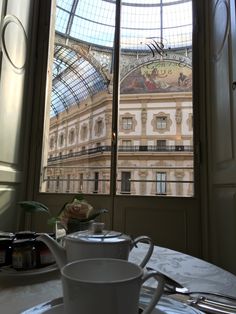 two cups and saucers sit on a table in front of a large glass window