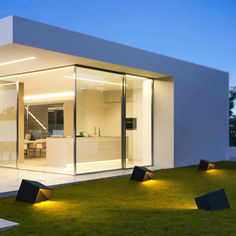 modern house with grass and lights on the lawn