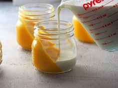 orange juice being poured into small glass jars