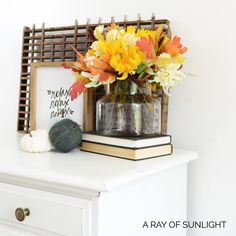 a vase filled with flowers sitting on top of a white dresser next to a sign