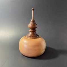 a small wooden container sitting on top of a gray table next to a black wall