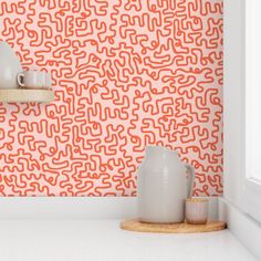 an orange and white wallpaper with some cups on the shelf in front of it