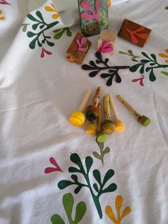 several wooden crayons on a white tablecloth with colorful flowers and leaves around them