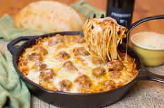 a skillet filled with spaghetti and meatballs being lifted from the casserole