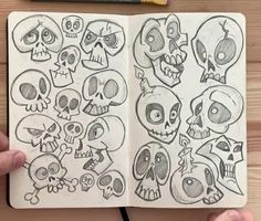 someone is holding an open notebook with skulls drawn on it and the pages are lined up