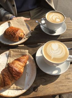 two plates with croissants on them next to a cup of cappuccino