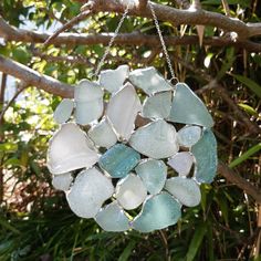 a glass ornament hanging from a tree branch with sea glass pieces on it