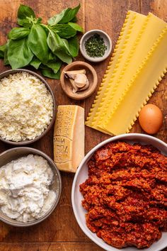 ingredients to make pasta laid out on a wooden table including eggs, cheese and spinach