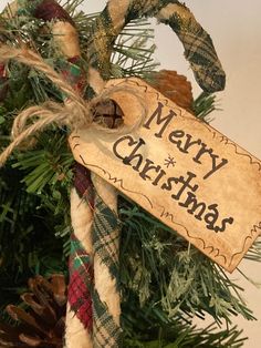 a christmas ornament hanging from the top of a tree with a merry christmas sign on it