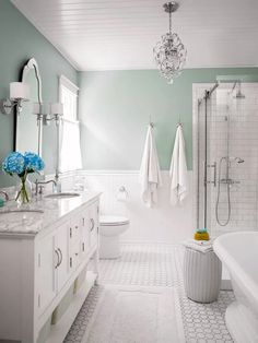 a bathroom with two sinks, a bathtub and a chandelier hanging from the ceiling