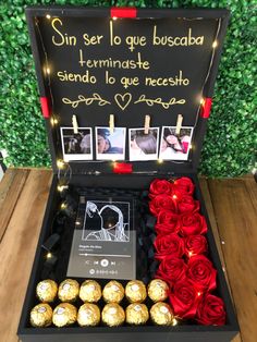 a box filled with chocolates and roses on top of a wooden table next to a sign