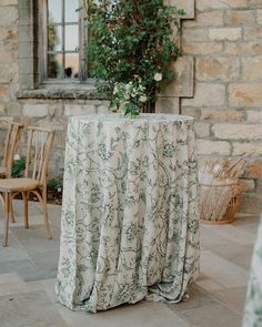 a table covered with a white cloth next to some chairs and a potted plant