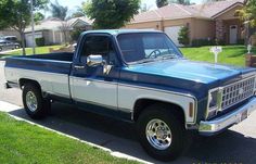 a blue and white pickup truck parked in front of a house