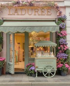 a store front with flowers on the outside and a cart in front that says laduree