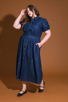 A washed denim midi dress featuring shirt collar, button down, short puff sleeve, front pockets and full skirt Details: Self : 90% Cotton 10% Polyester Size & Fit - Model is 5`8" And Wearing Size Small- Measurements Taken From Size Small- Approx. Length: 51" Casual Short Sleeve Cotton Denim Dress, Casual Midi Length Denim Dress With Pockets, Denim Blue Short Sleeve Shirt Dress, Denim Midi Shirt Dress With Pockets, Denim Midi Length Shirt Dress With Pockets, Denim Midi Dress With Pockets And Short Sleeves, Dark Wash Short Sleeve Denim Dress With Button Closure, Dark Wash Relaxed Fit Short Sleeve Denim Dress, Dark Wash Relaxed Fit Denim Dress With Short Sleeves