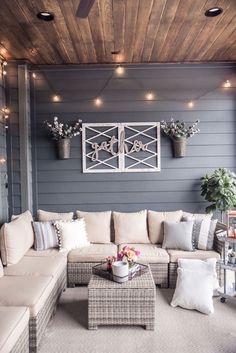 a living room with couches and pillows on the floor, lights hanging from the ceiling