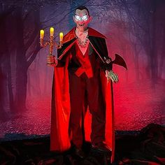 a man dressed as dracula holding two candles in his hand and wearing a red cape