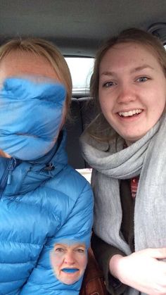 two women sitting in the back seat of a car with their faces painted on them