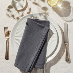 a white plate topped with a napkin next to a fork and knife on top of a table