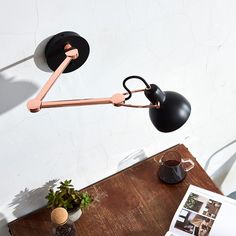 a table with a lamp, coffee cup and magazine on it next to a potted plant