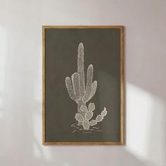 a black and white drawing of a cactus in a wooden frame hanging on the wall