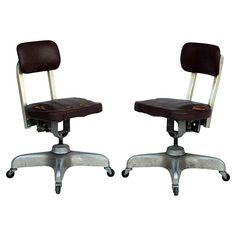 two office chairs sitting side by side on casteors with wheels and leather seat covers