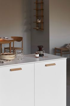 a white cabinet sitting next to a table with plates and cups on top of it