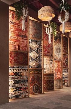 a room filled with lots of different rugs and lamps hanging from the ceiling next to each other