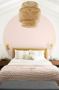 a bedroom with pink walls and white bedding in front of a round light fixture