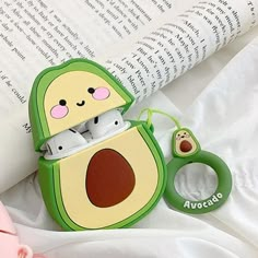 an avocado airpods case sitting on top of a book next to a pair of ear buds