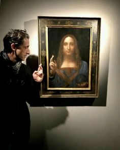 a man standing next to a painting on display