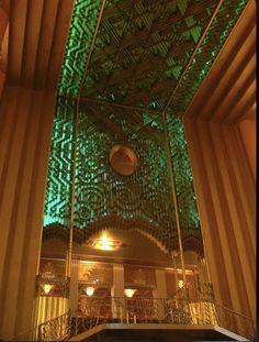 the inside of a building that has green lights on it and some stairs in front of it