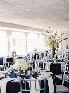 the tables are set with white flowers and blue linens for an elegant wedding reception