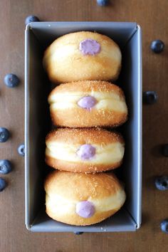 four donuts in a box with blueberries on the side