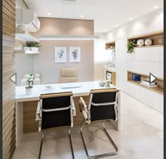 two chairs are sitting at a table in the middle of a room with built - in shelving