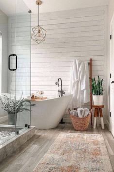 a bathroom with white walls and wood flooring, a large rug on the floor