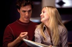 a man and woman sitting next to each other looking at something on a paper plate