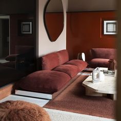 a living room filled with red couches and a mirror on the wall above them