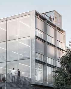 two men standing on the balcony of a building with glass walls and balconies