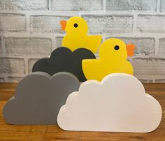 two yellow rubber ducks sitting on top of some gray and white cloud shaped paper clouds