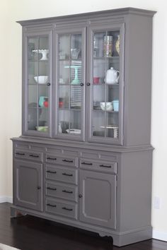 a gray china cabinet with glass doors and drawers