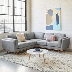 a living room with a sectional couch and coffee table in front of a large window