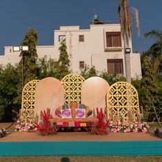 an outdoor stage set up in front of a building with flowers and plants on it