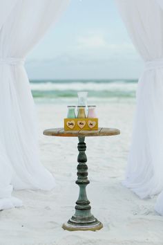 a tray with drinks sitting on top of a table next to a window at the beach