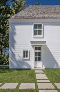 a white house sitting on top of a lush green field