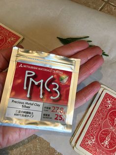 a hand holding a packet of m & s playing cards next to two matching playing cards