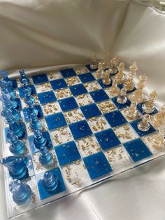 a glass chess board with blue and white pieces on it, all covered in gold flakes