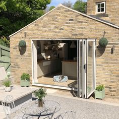 an outdoor kitchen is built into the side of a brick building with doors open to let in natural light